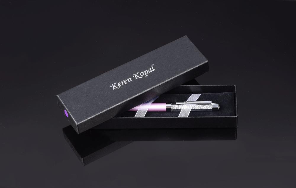 A luxurious purple pen adorned with sparkling Swarovski crystals, elegantly displayed in a black gift box.