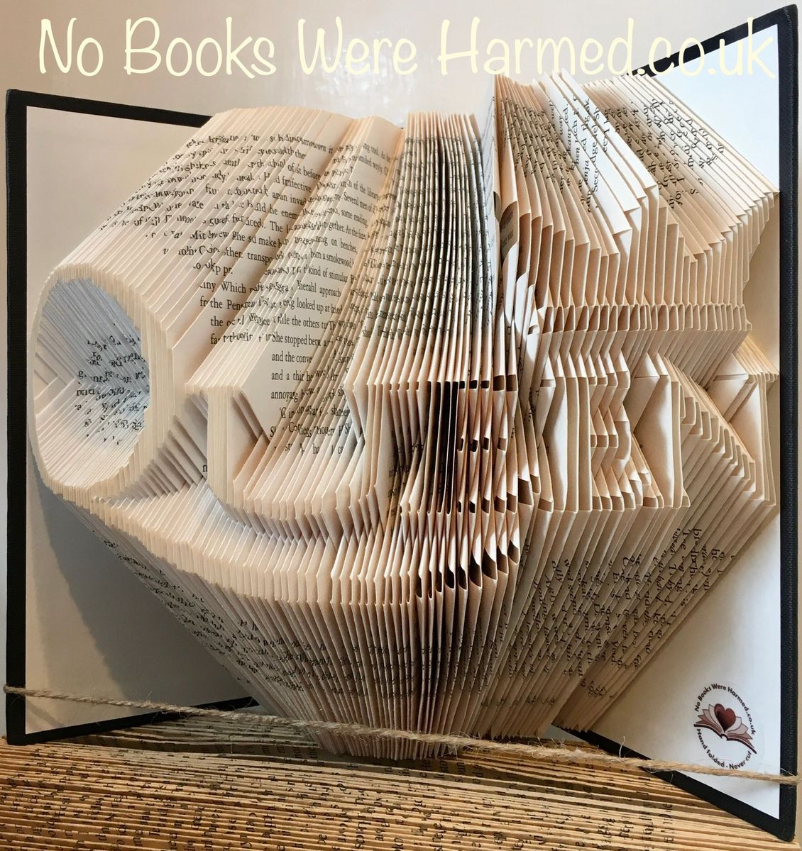 Handcrafted art piece of a queen wearing a crown, made from vintage book pages, showcasing intricate folds and unique design.