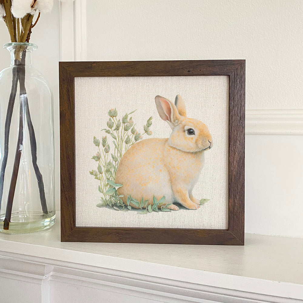 Rabbit in Grass Framed Sign with a stylized wood frame, featuring a charming rabbit design on a linen-look background.