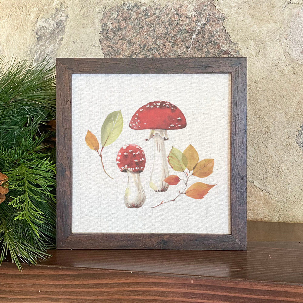 A beautifully framed sign featuring red capped mushrooms on a linen-look background, perfect for home decor.