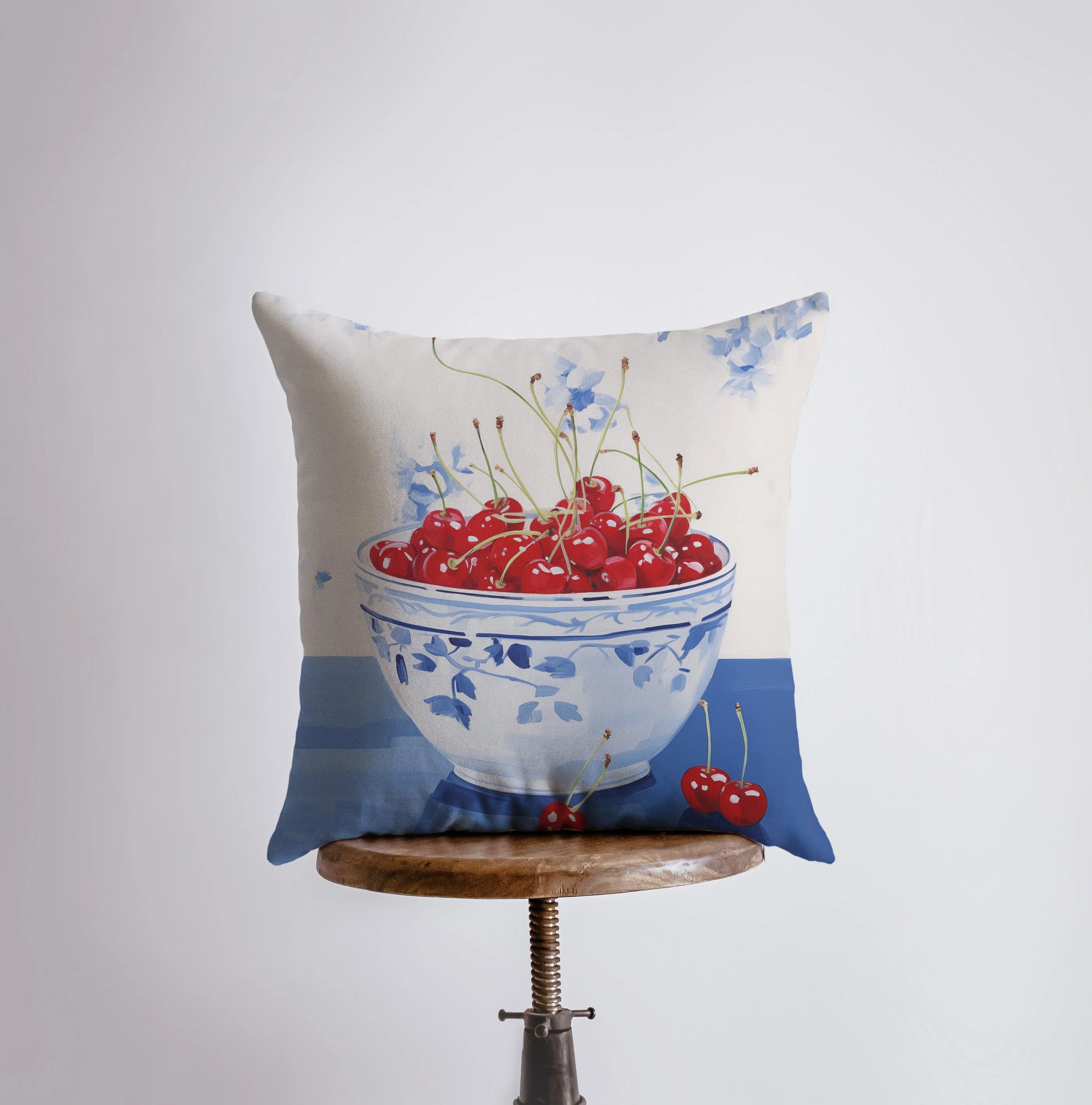 A vibrant Red Cherry Bowl pillow featuring a gouache painting design, showcasing cherries in a bowl against a white background.