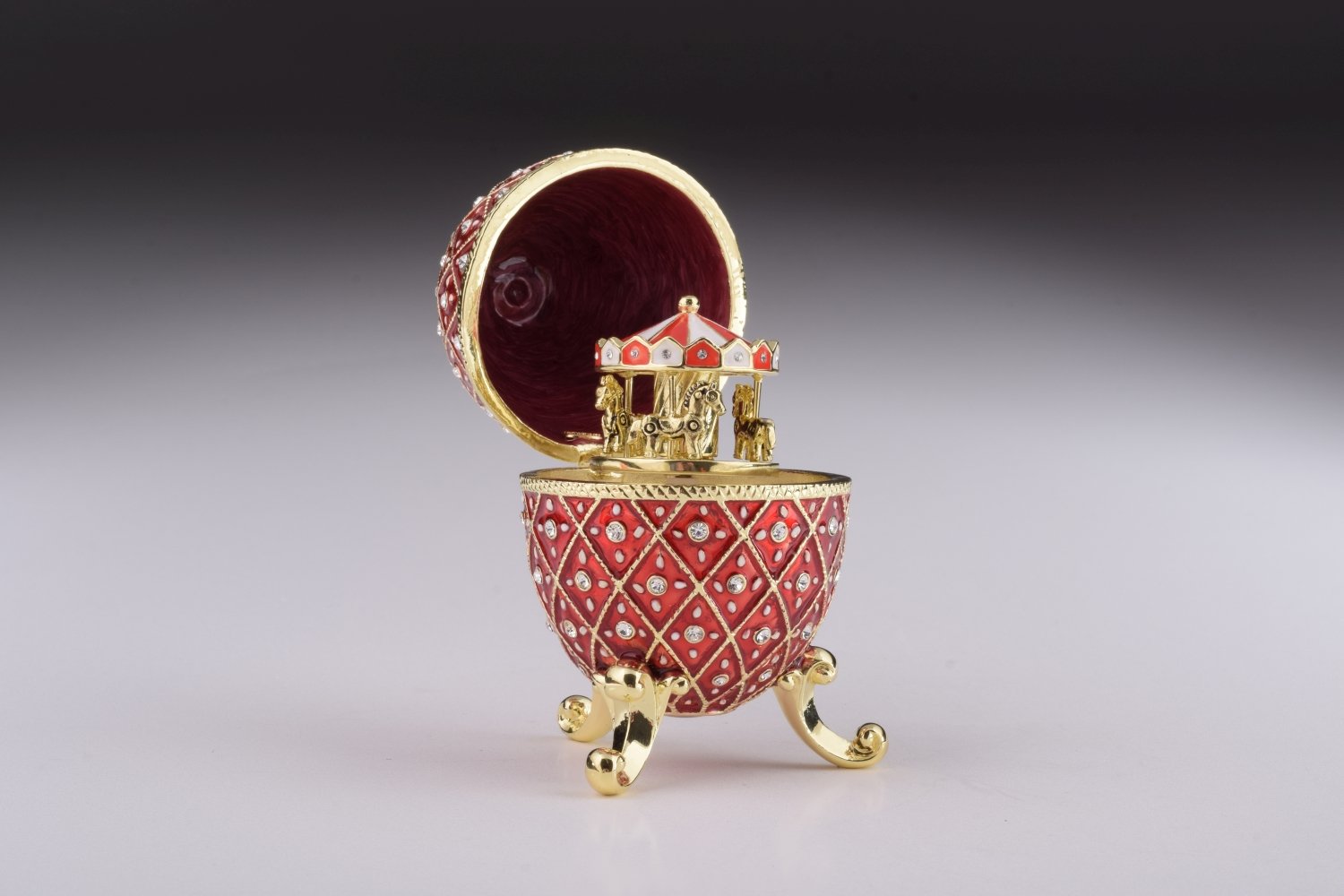 A stunning Red Faberge Egg trinket box featuring a horse carousel surprise inside, adorned with Austrian crystals and 24K gold plating.