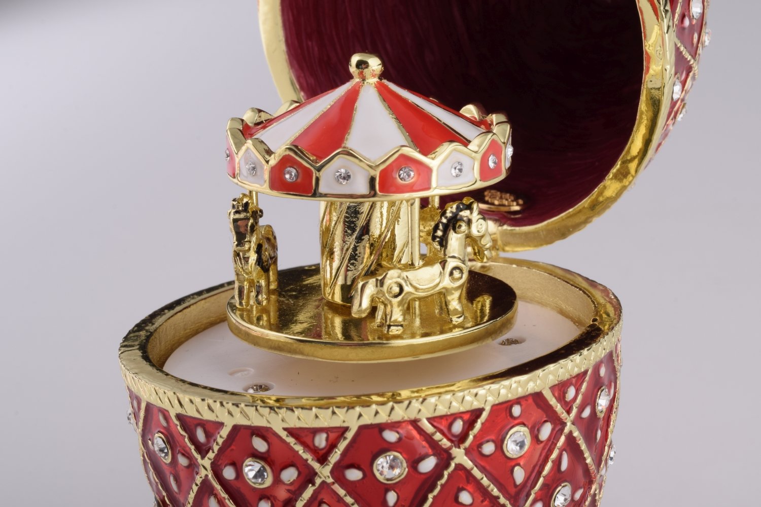 A stunning Red Faberge Egg trinket box featuring a horse carousel surprise inside, adorned with Austrian crystals and 24K gold plating.