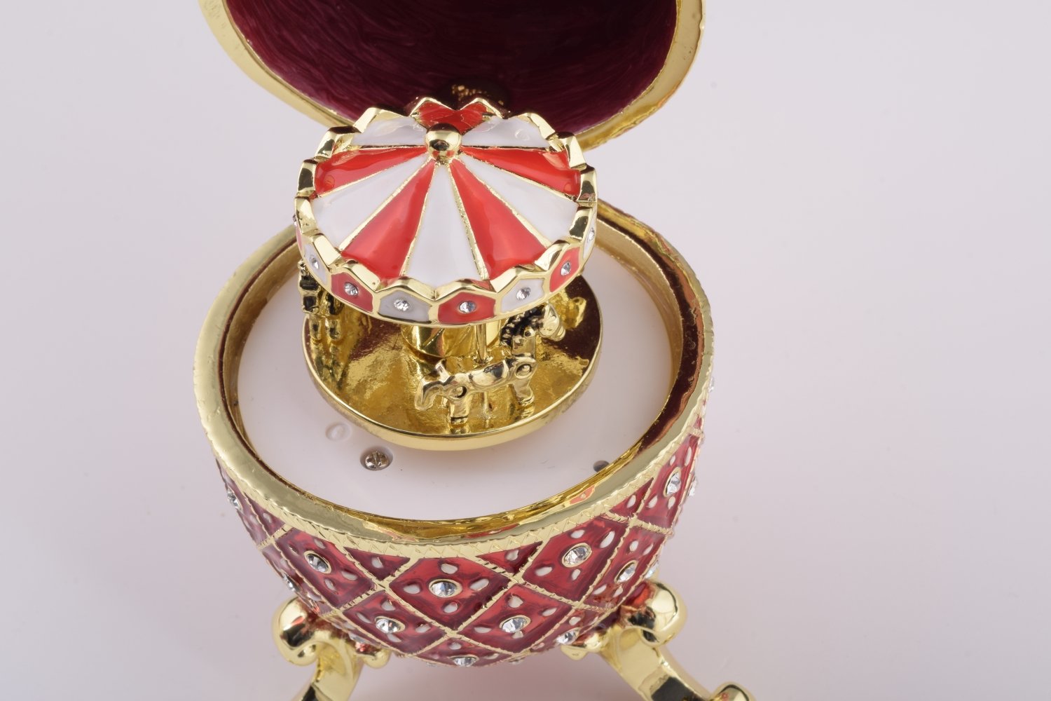 A stunning Red Faberge Egg trinket box featuring a horse carousel surprise inside, adorned with Austrian crystals and 24K gold plating.