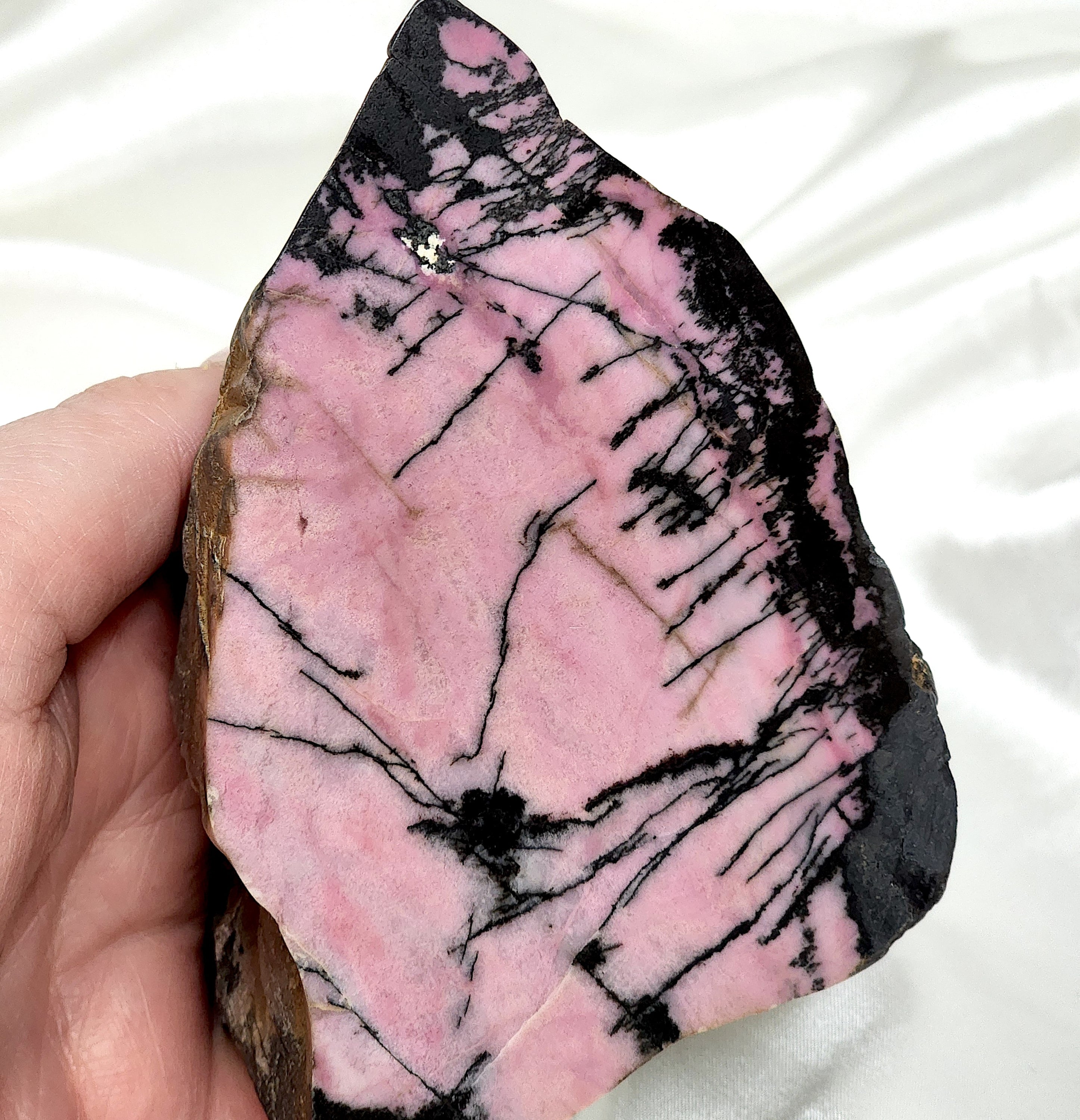 A collection of unique Rhodonite Freeform Slabs showcasing their pink and black patterns, perfect for emotional healing and decoration.