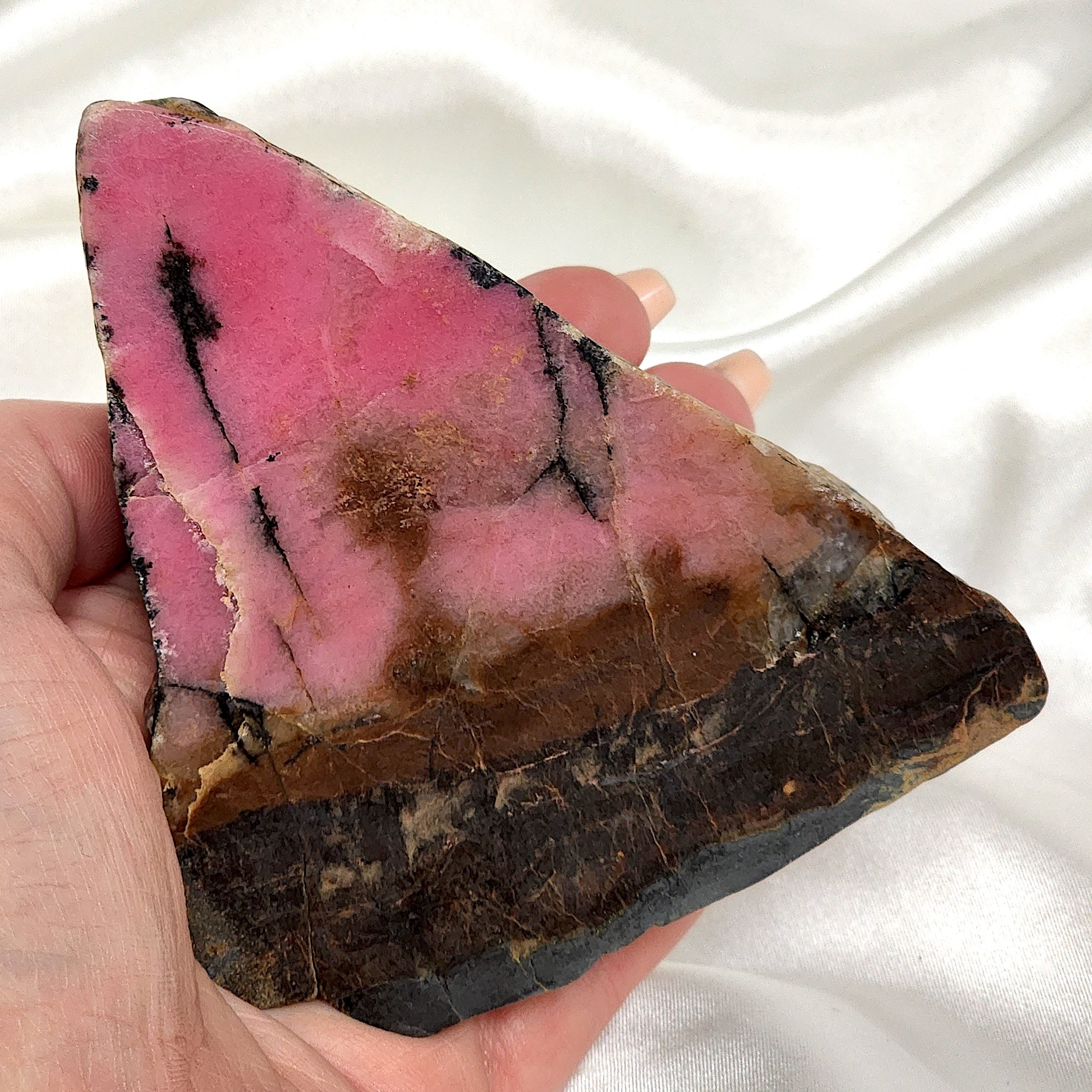 A collection of unique Rhodonite Freeform Slabs showcasing their pink and black patterns, perfect for emotional healing and decoration.