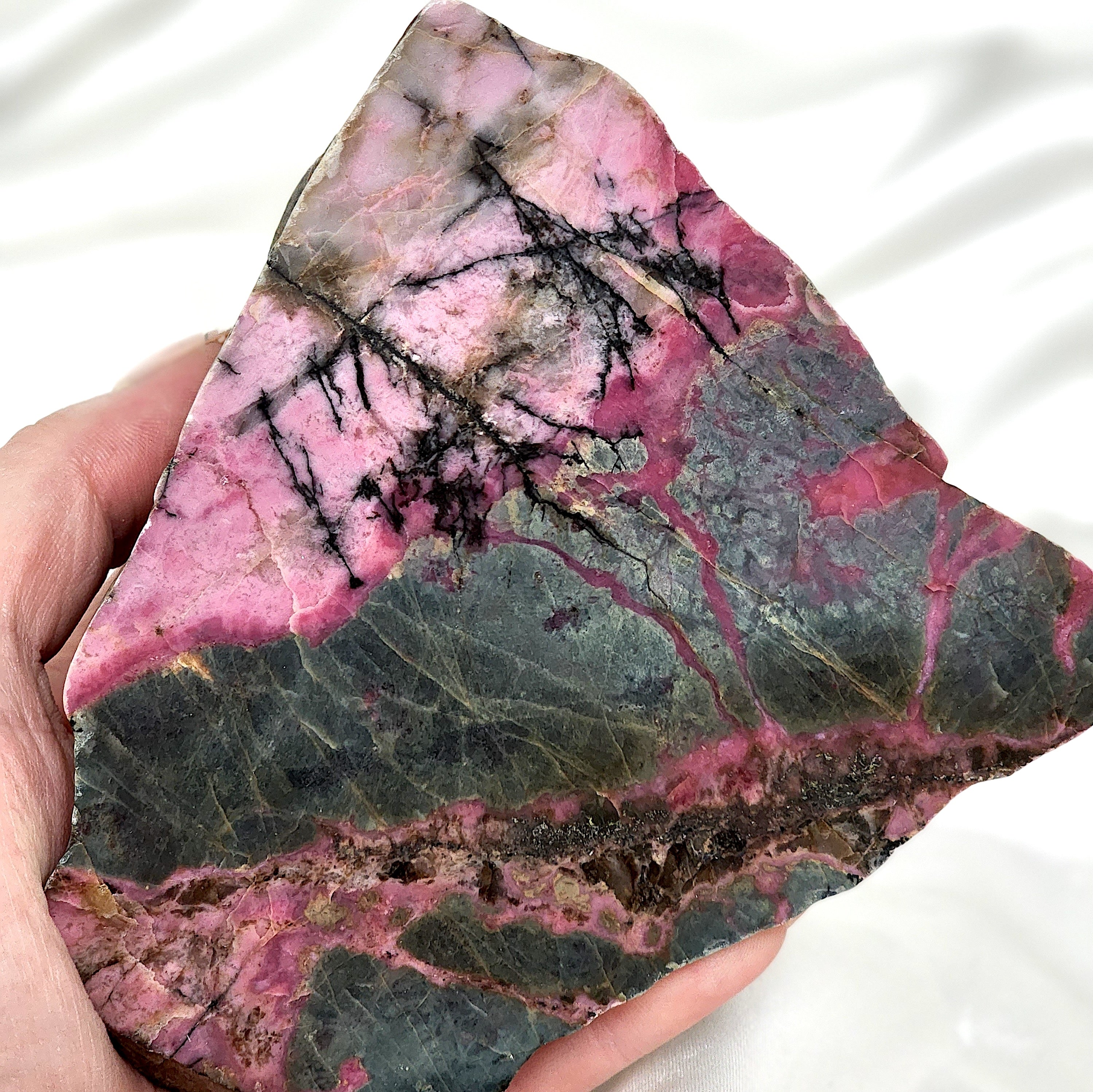 A collection of unique Rhodonite Freeform Slabs showcasing their pink and black patterns, perfect for emotional healing and decoration.