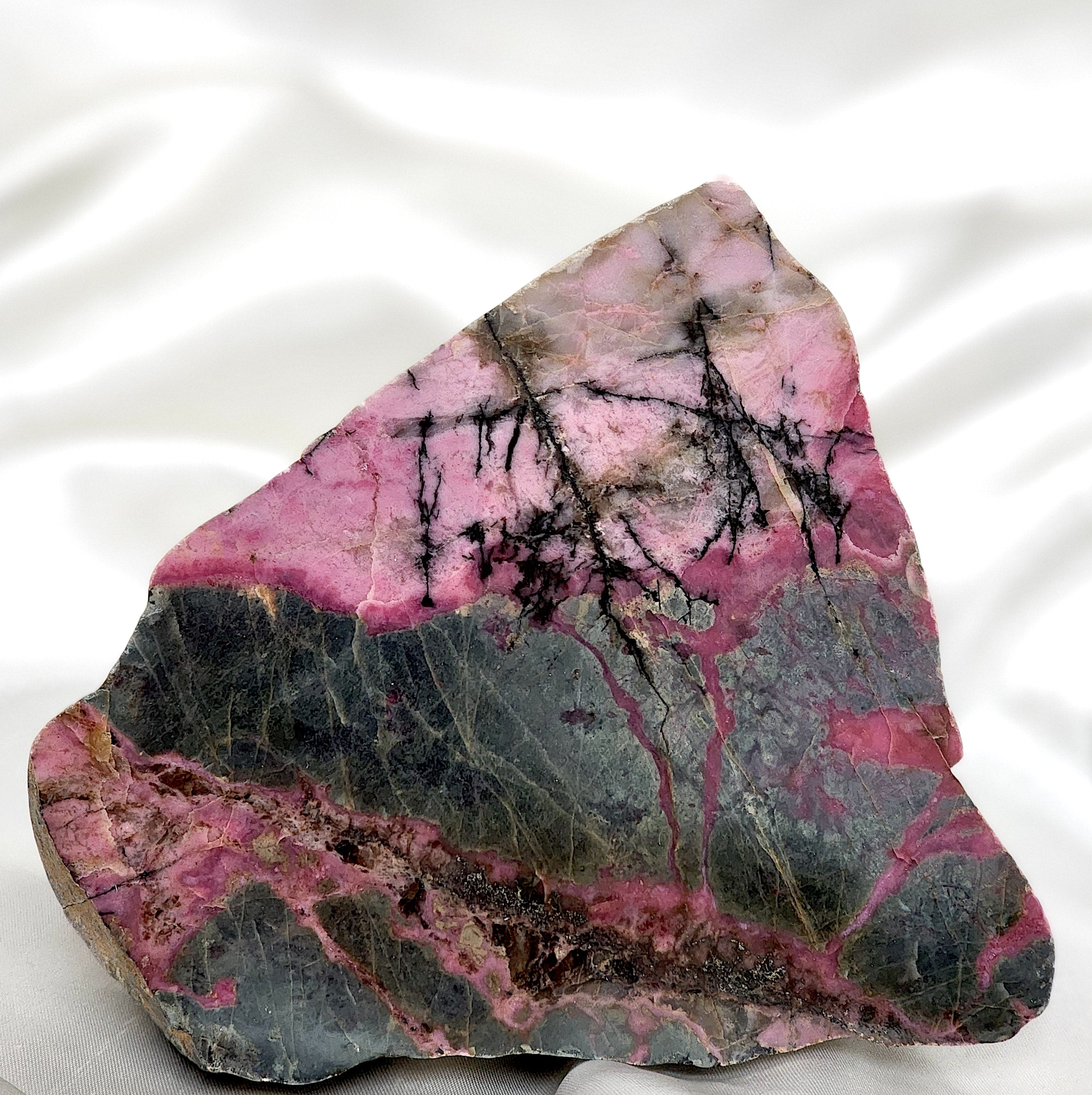 A collection of unique Rhodonite Freeform Slabs showcasing their pink and black patterns, perfect for emotional healing and decoration.