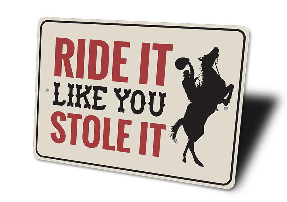 A decorative 'Ride It Like You Stole It' sign made of high-quality aluminum, featuring vibrant colors and a rustic design, perfect for barn or farmhouse decor.