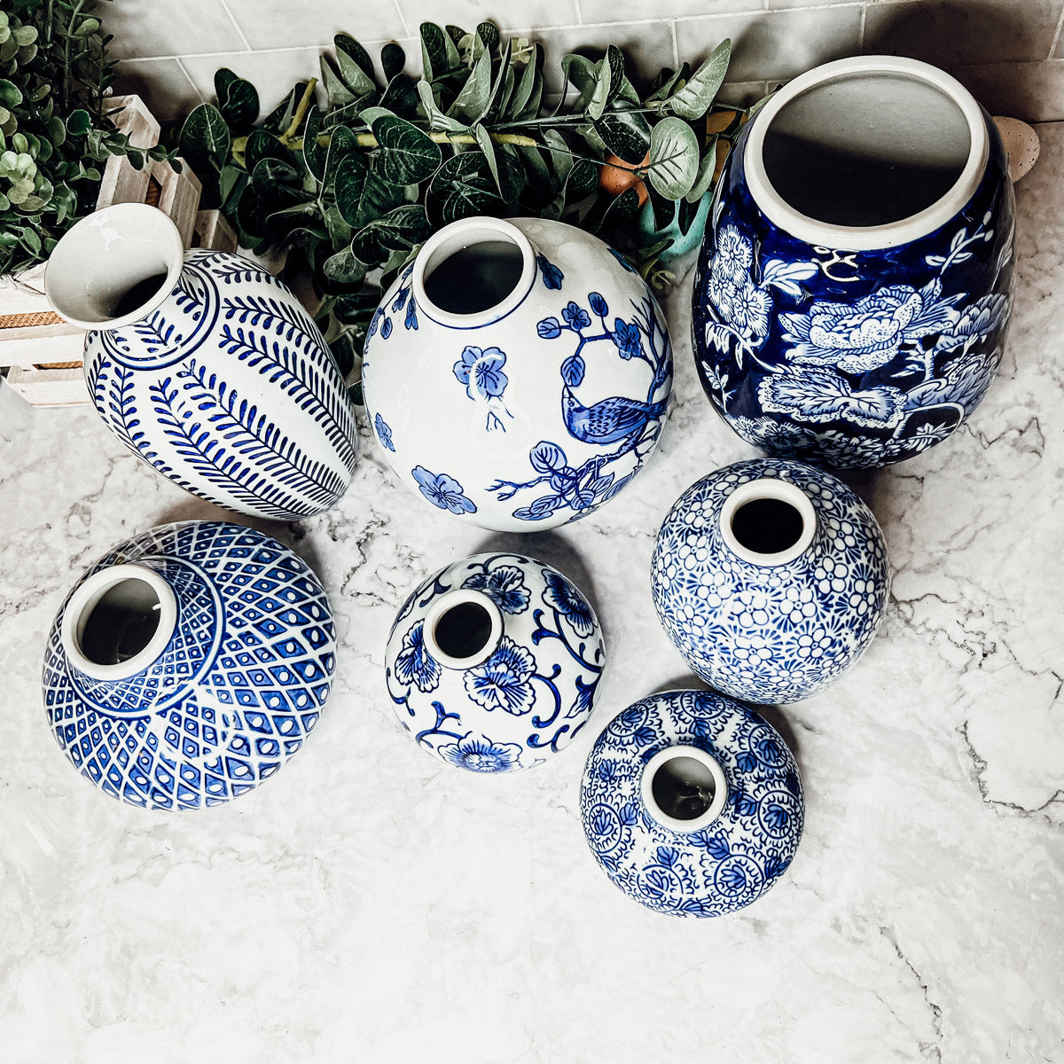 A collection of Samira Blue Vases featuring hand-painted porcelain in classic blue and white designs, showcasing various sizes and styles.