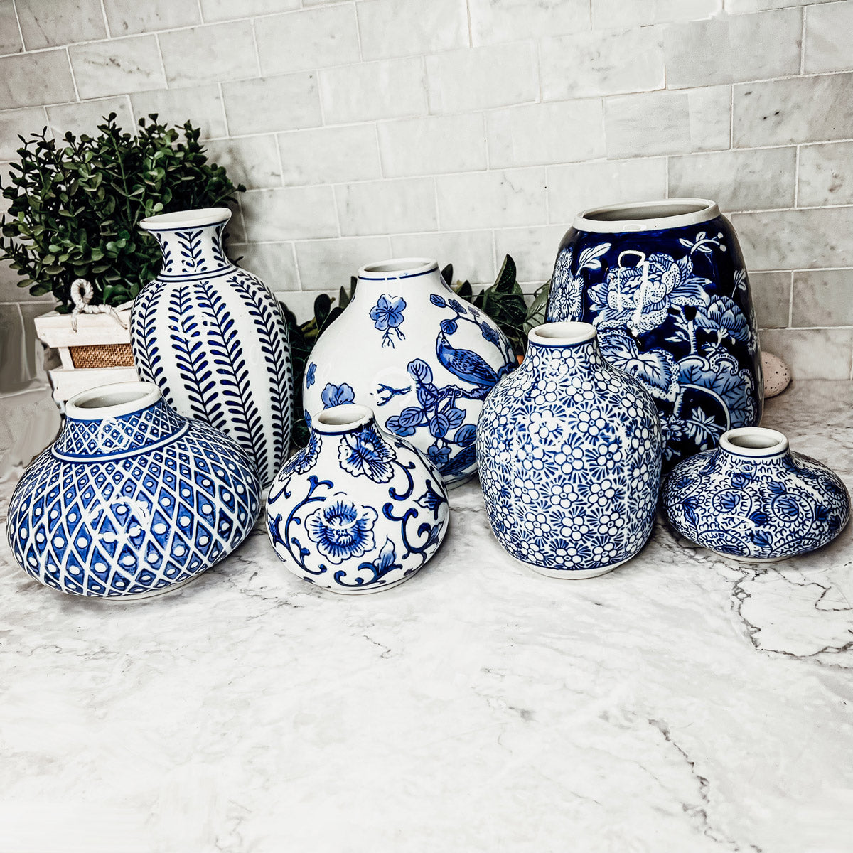 A collection of Samira Blue Vases featuring hand-painted porcelain in classic blue and white designs, showcasing various sizes and styles.