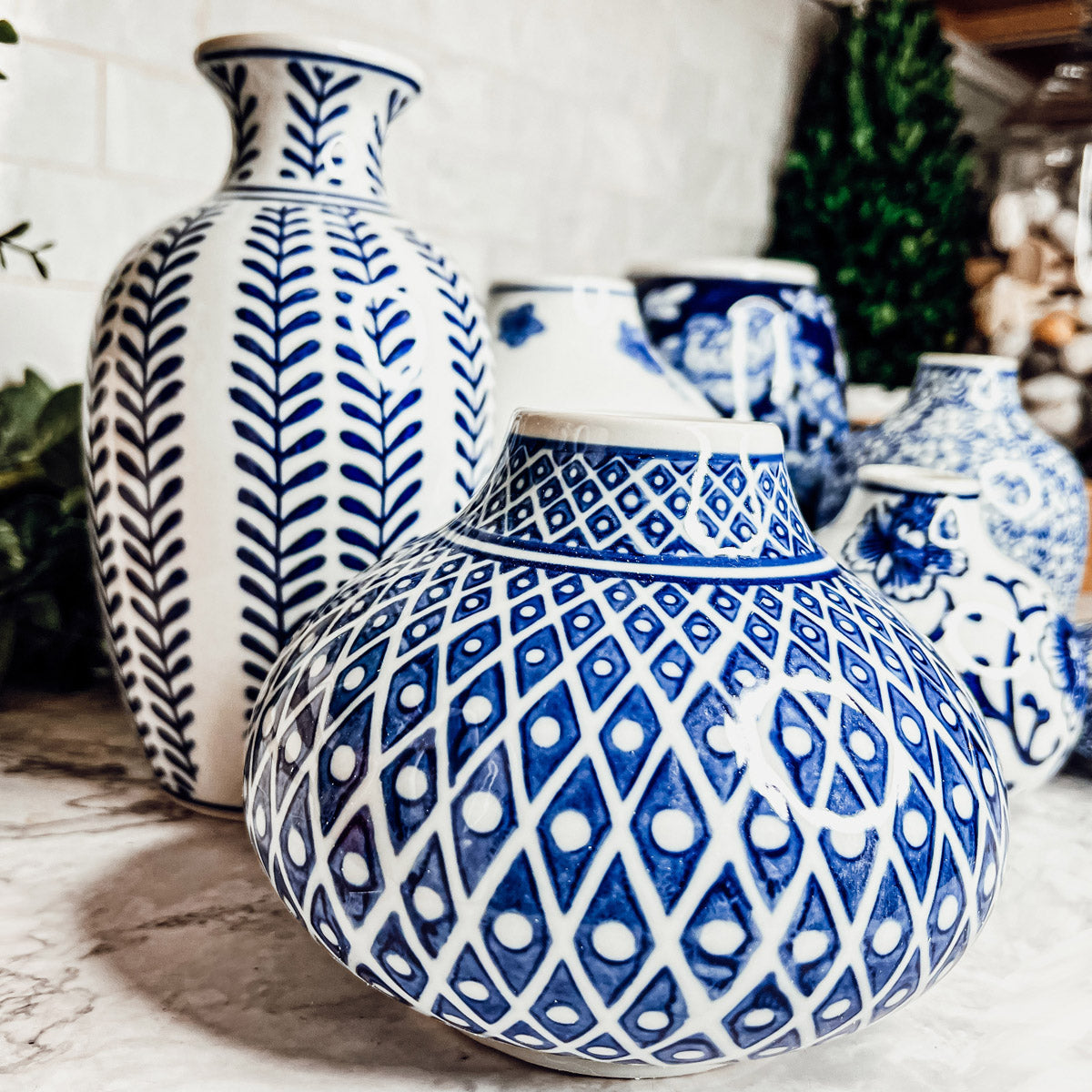 A collection of Samira Blue Vases featuring hand-painted porcelain in classic blue and white designs, showcasing various sizes and styles.