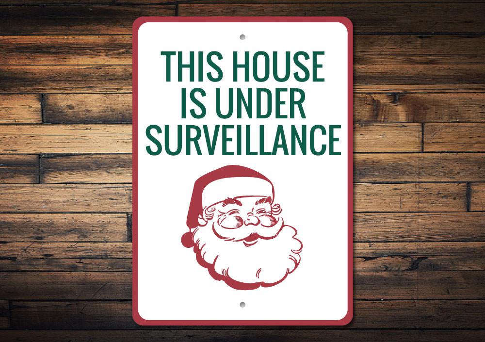 A festive Santa Surveillance Sign made of durable aluminum, featuring a whimsical design perfect for holiday decorations.