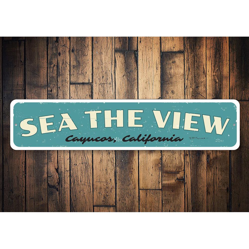 A decorative Sea The View Sign made of high-quality aluminum, featuring a beach-themed design, perfect for coastal decor.