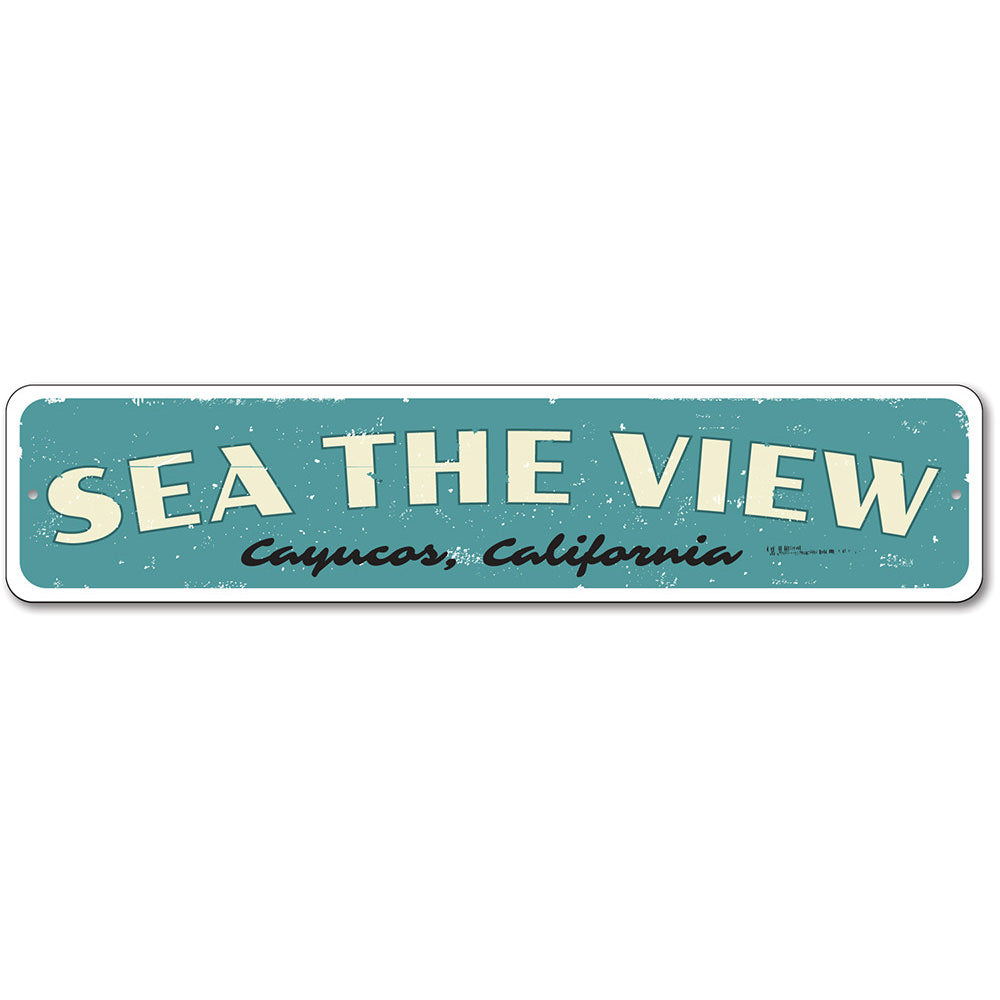 A decorative Sea The View Sign made of high-quality aluminum, featuring a beach-themed design, perfect for coastal decor.