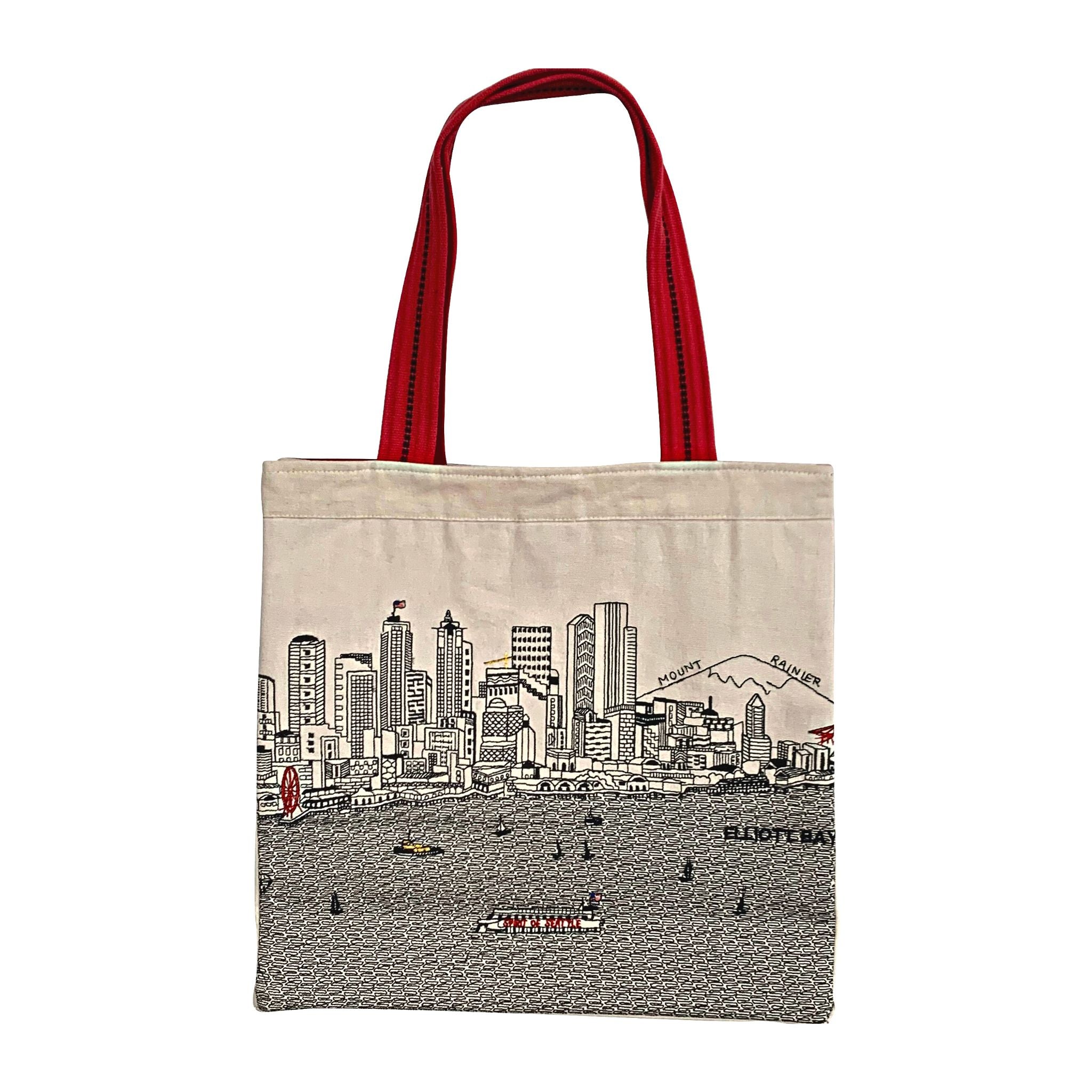 Seattle Tote Bag featuring an embroidered skyline design on cream and black cotton canvas with red waterproof lining and straps.