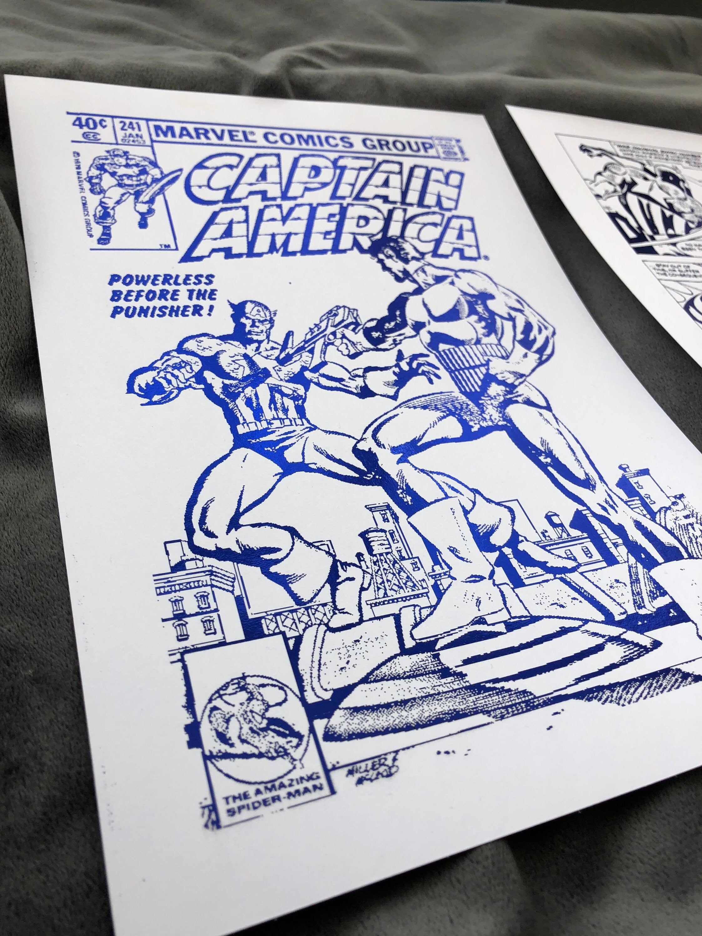 Set of 2 Captain America foil prints featuring vibrant comic cover and comic strip designs, showcasing the iconic superhero in a metallic finish.