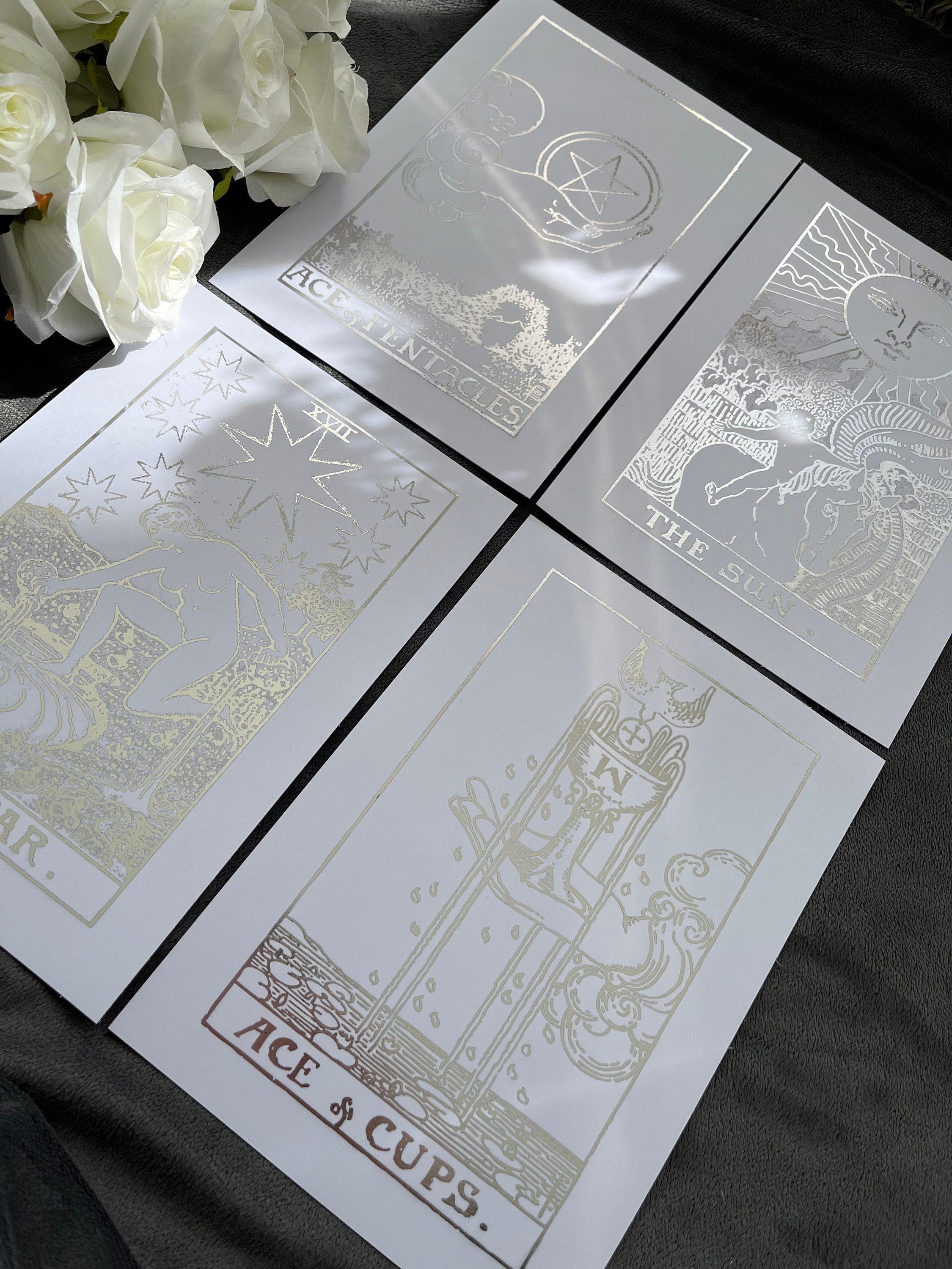 Set of 4 tarot card foil prints featuring Ace of Cups, The Sun, The Star, and Ace of Pentacles in shimmering silver accents.