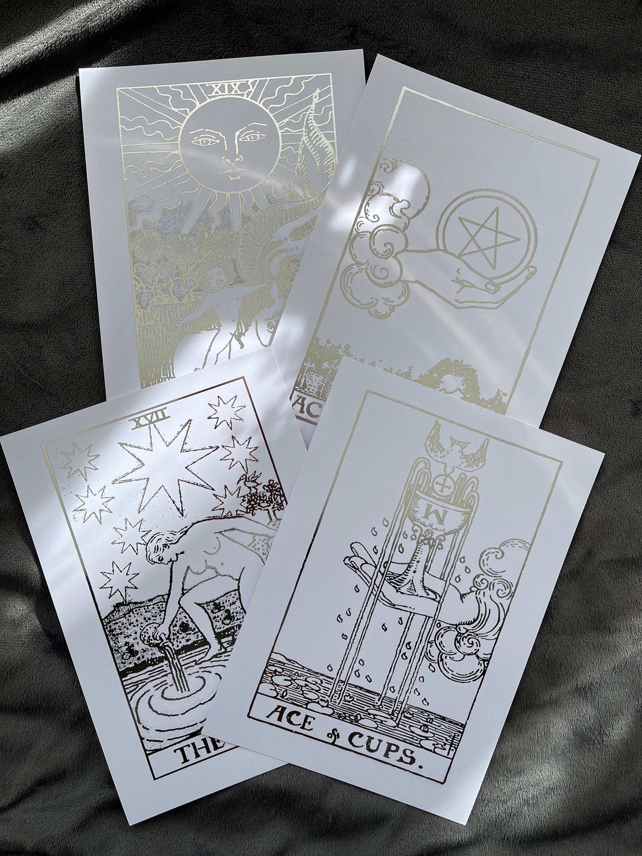 Set of 4 tarot card foil prints featuring Ace of Cups, The Sun, The Star, and Ace of Pentacles in shimmering silver accents.