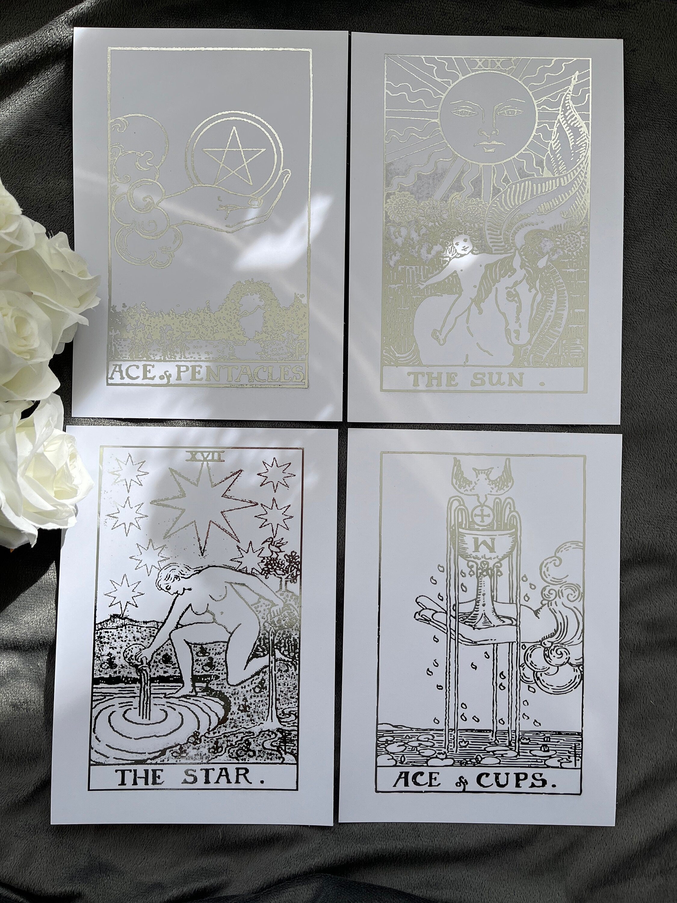 Set of 4 tarot card foil prints featuring Ace of Cups, The Sun, The Star, and Ace of Pentacles in shimmering silver accents.