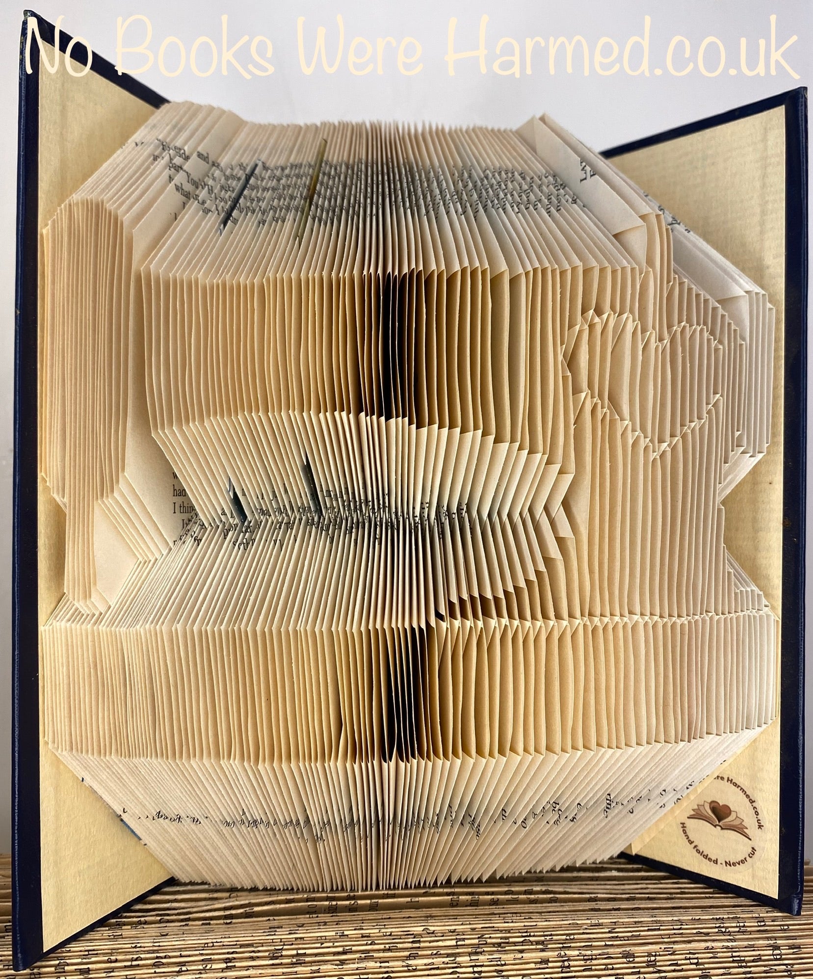 Artistic representation of a sewing machine made from hand-folded pages of vintage books, showcasing unique textures and colors.