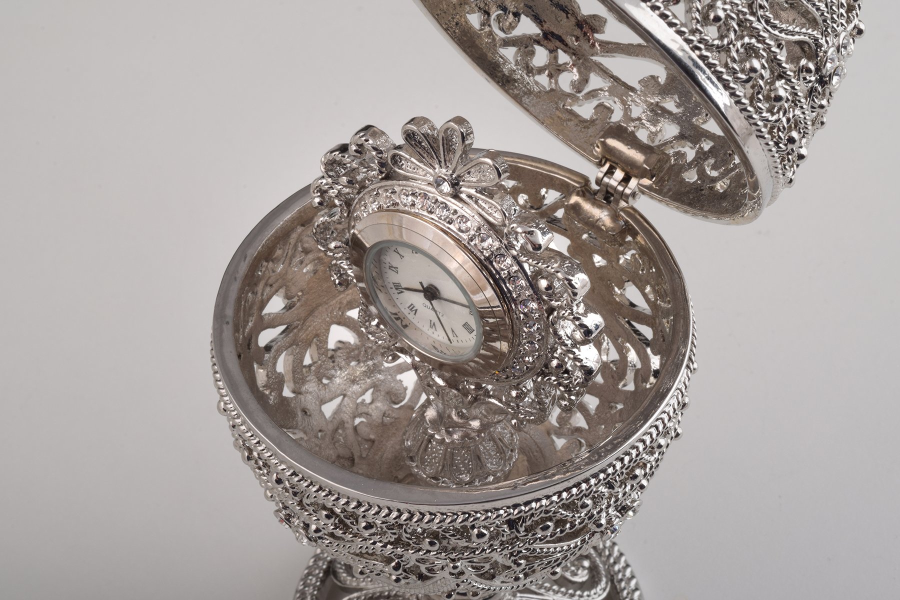 A beautifully crafted Silver Faberge Egg trinket box with a clock inside, adorned with Austrian crystals and plated in 24K Gold or 925 Silver.