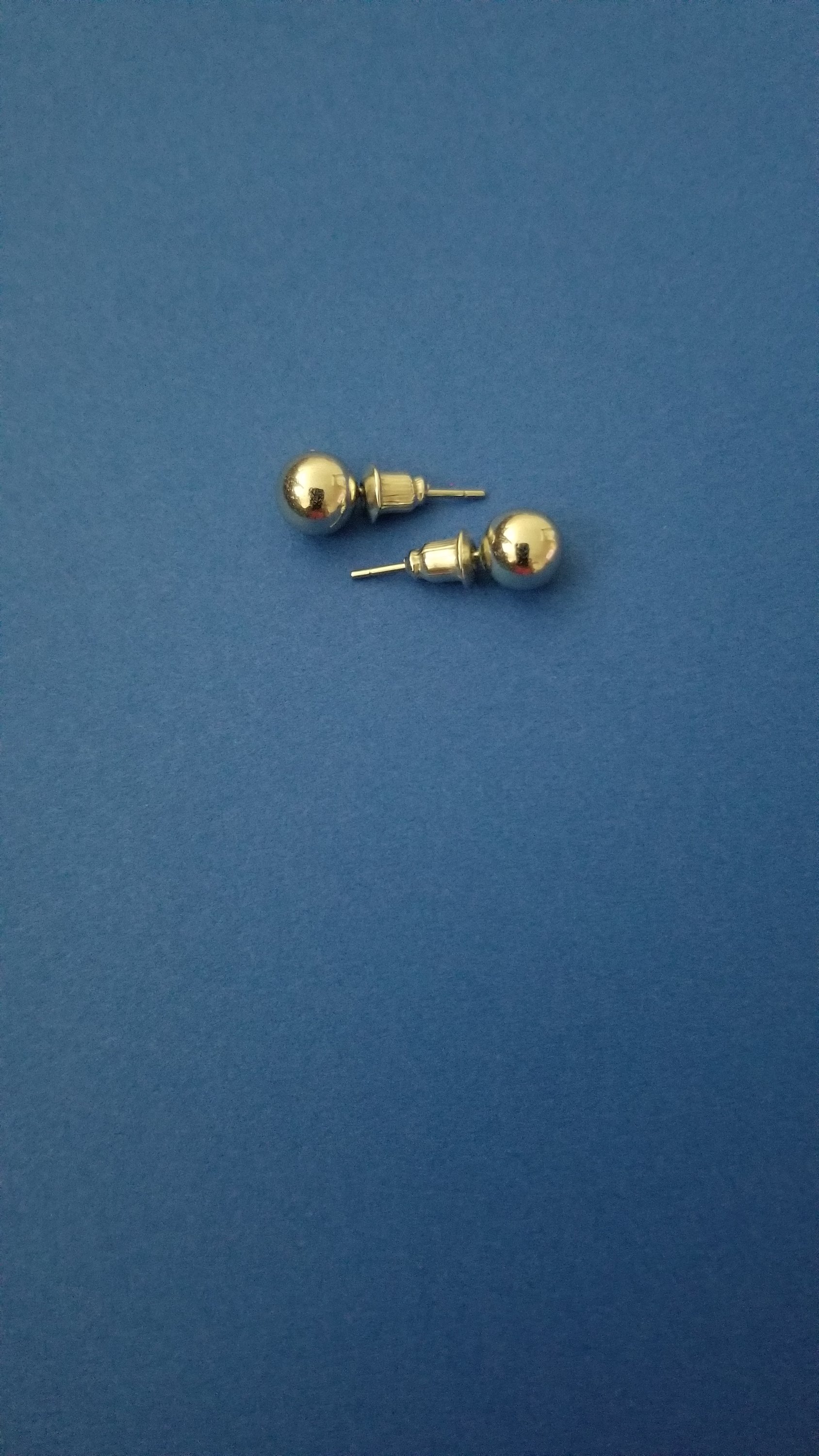 A pair of silver-colored sphere-shaped ear studs in various sizes, showcasing their elegant design.