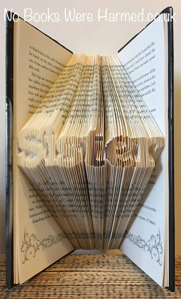 Hand-folded book art titled 'Sister', crafted from vintage books, showcasing intricate folds and unique colors.