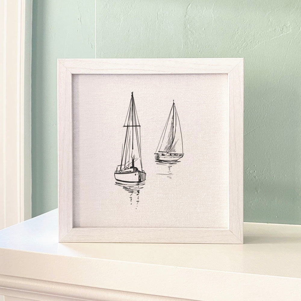 A beautifully framed sign featuring sketched sailboats, with a linen-look background and available in walnut or white-washed frame.