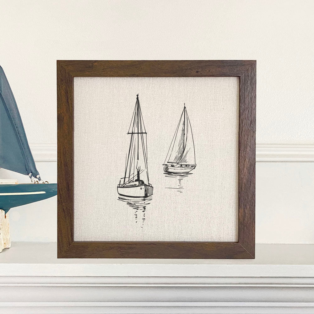 A beautifully framed sign featuring sketched sailboats, with a linen-look background and available in walnut or white-washed frame.