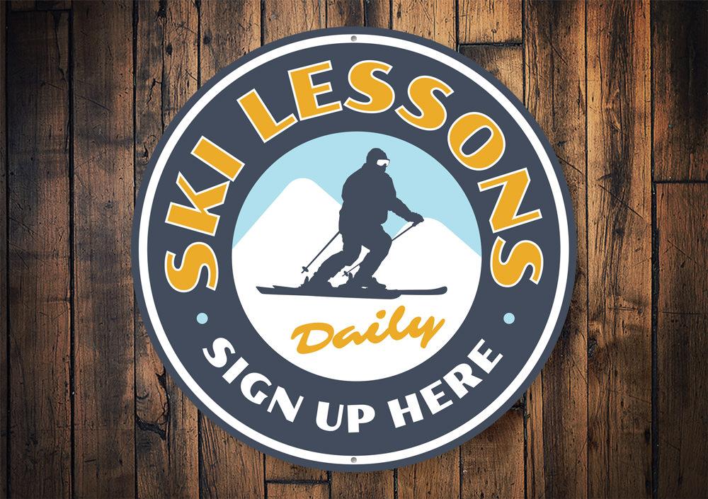 A decorative Ski Lessons Circle Sign made of high-quality aluminum, featuring a ski-themed design, perfect for wall decor in ski lodges or homes.