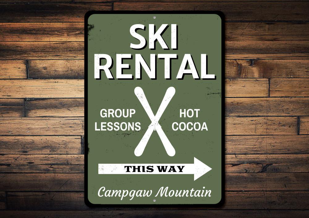 A decorative Ski Rental This Way Sign made of durable aluminum, featuring customizable text and pre-drilled holes for easy mounting.