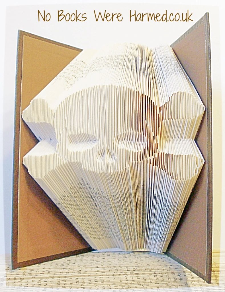 Hand-folded Skull & Crossbones art made from vintage book pages, showcasing intricate designs and unique colors.