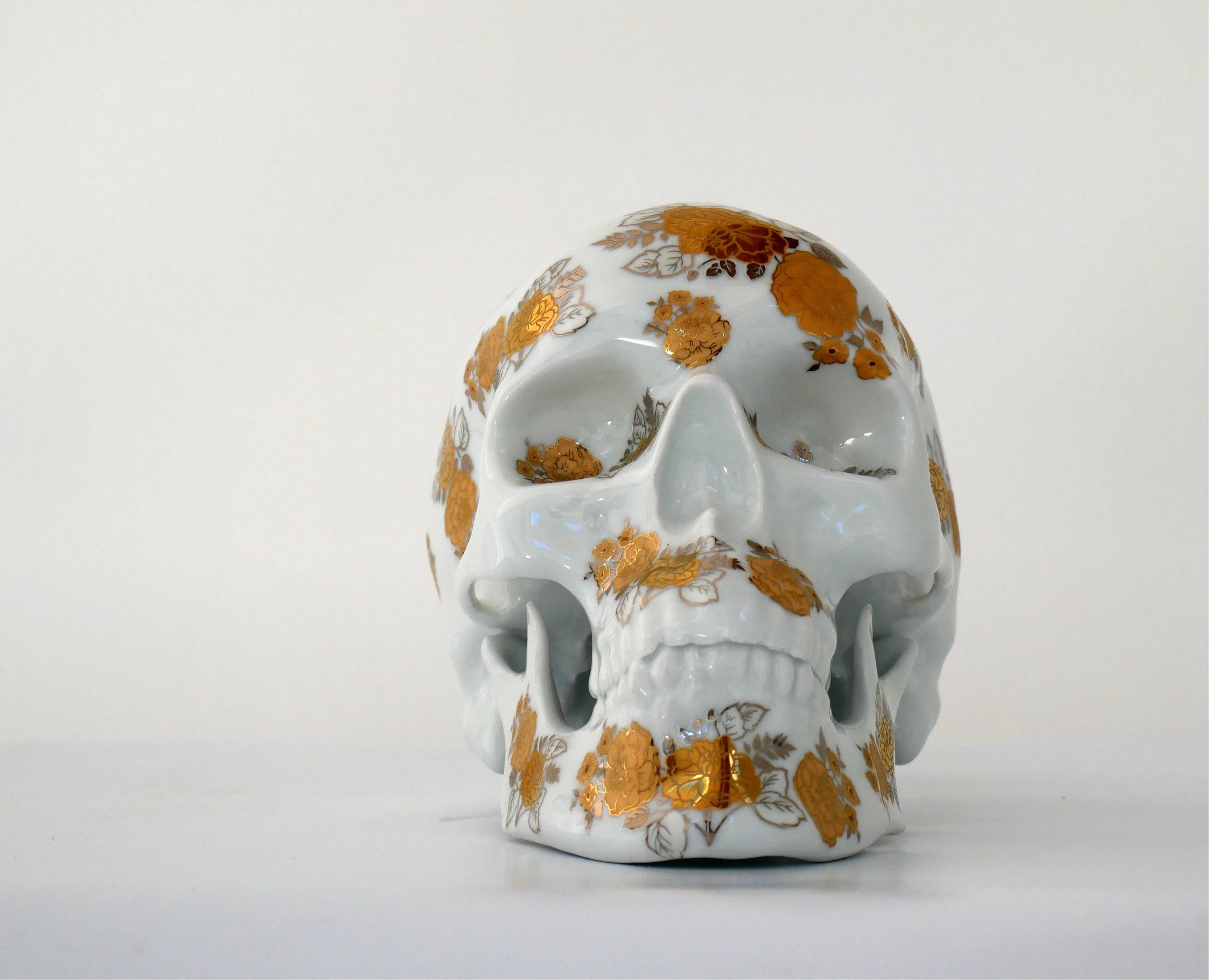 A unique Skull Gold Flowers art piece by NooN, crafted from extra white porcelain with gold floral accents, showcasing its intricate design.