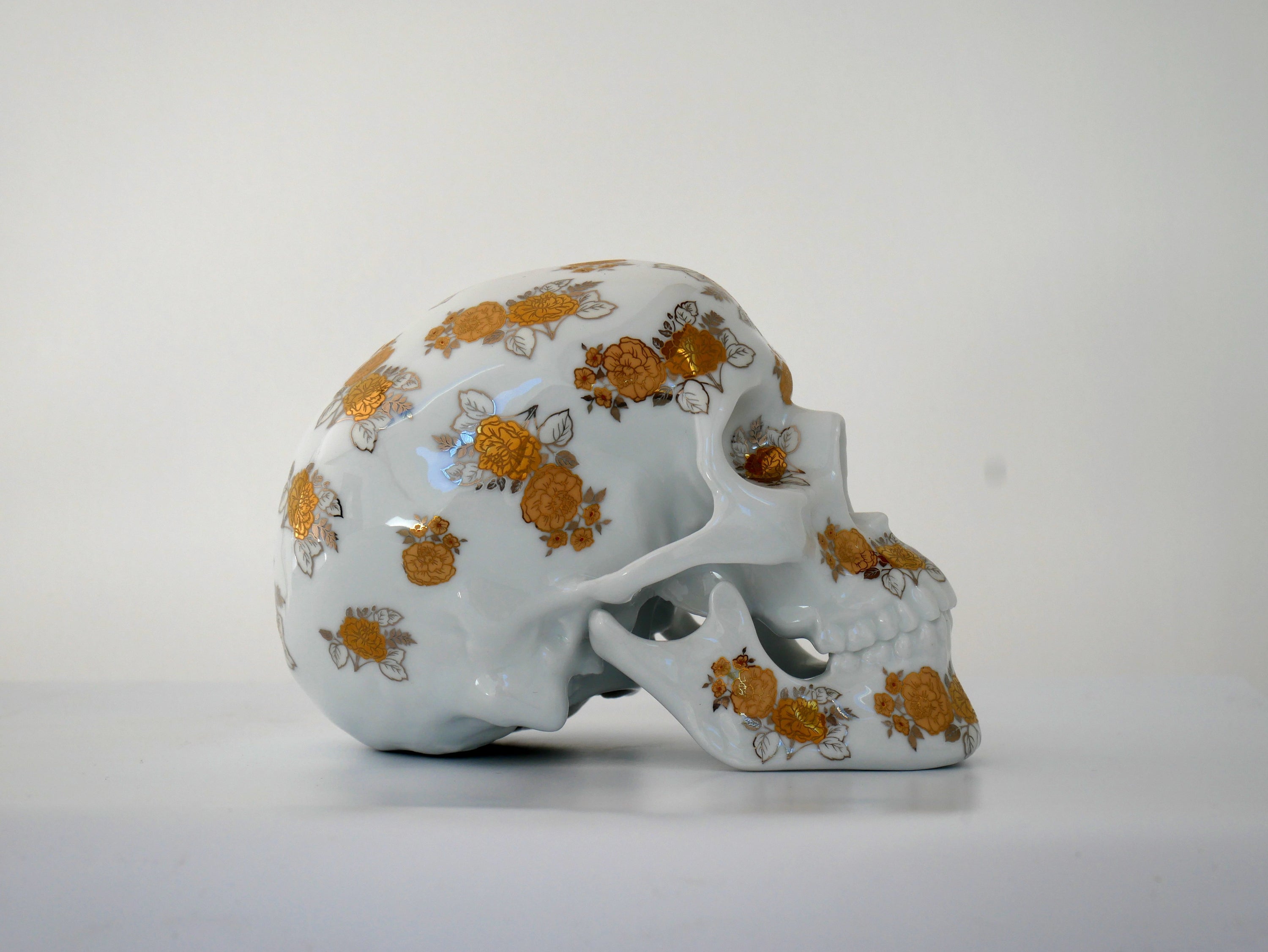 A unique Skull Gold Flowers art piece by NooN, crafted from extra white porcelain with gold floral accents, showcasing its intricate design.