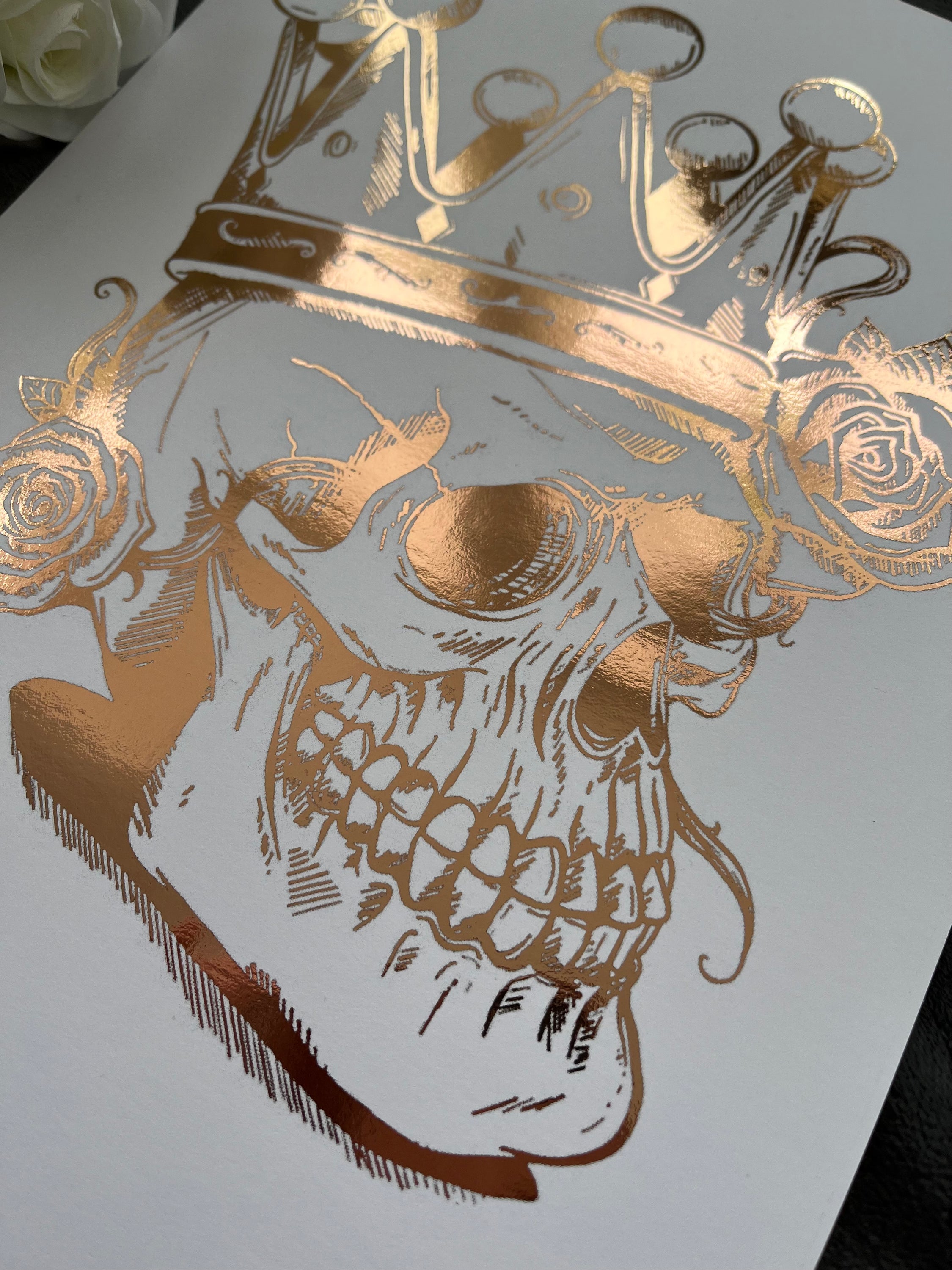 A striking rose gold foil print featuring a skull adorned with a majestic crown, showcasing intricate details and luxurious accents.