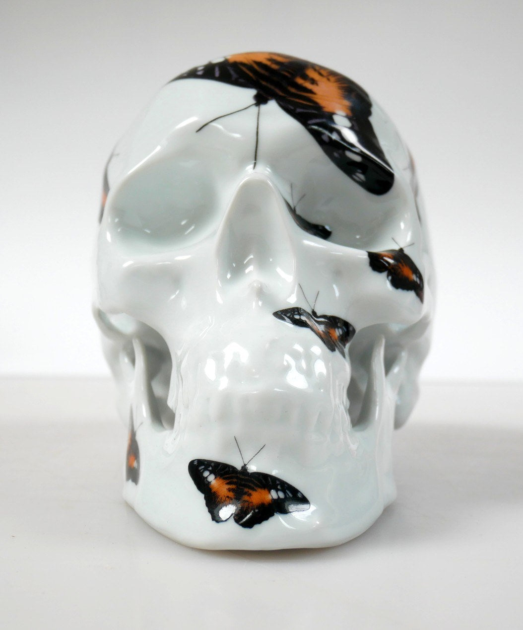 A unique Skull Orange Butterfly art piece by NooN, crafted from extra white porcelain, showcasing vibrant colors and intricate details.