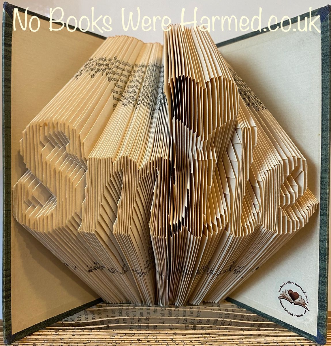 Unique hand-folded book art featuring a love heart design, crafted from vintage books, showcasing intricate folds and textures.