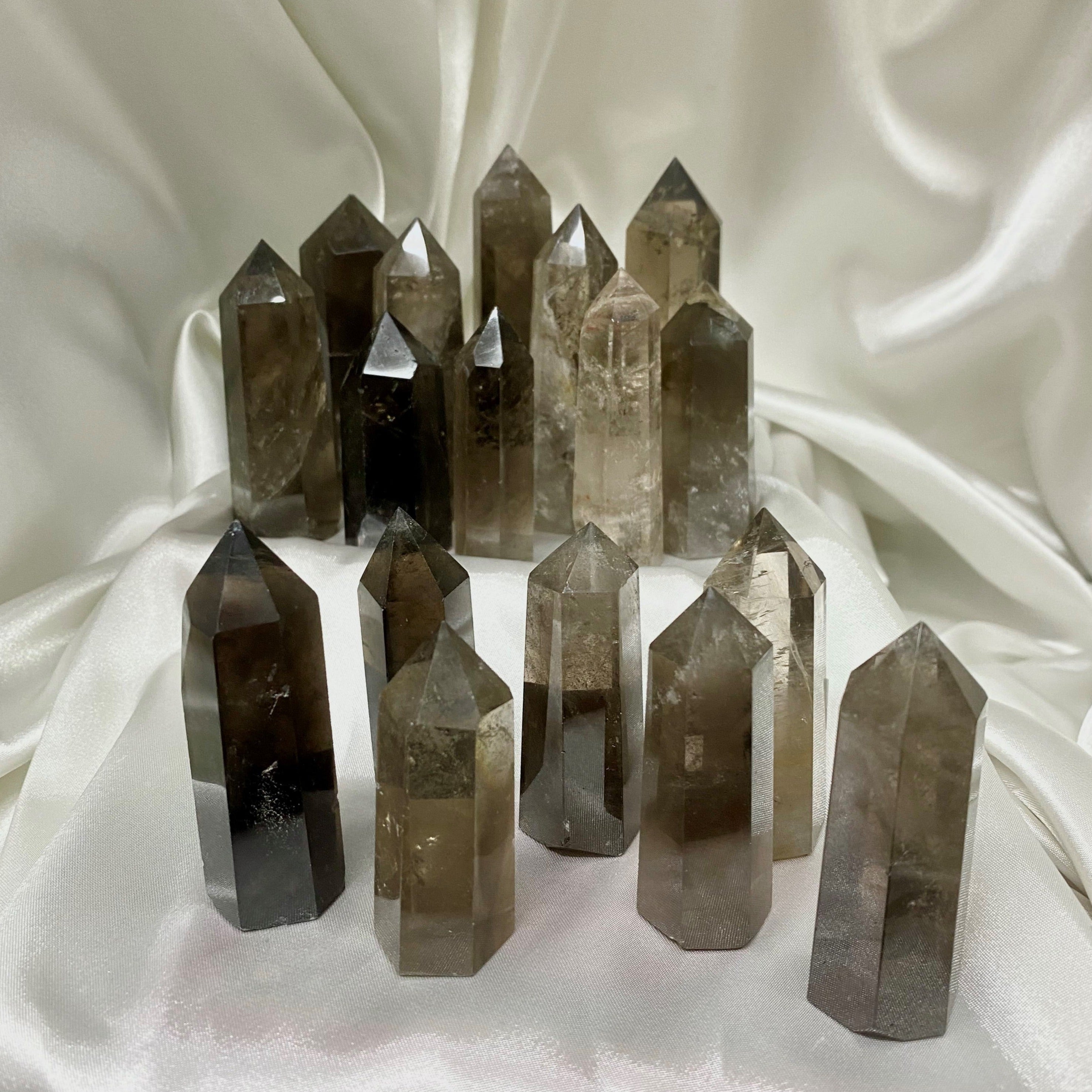 A hand-carved Smoky Quartz Generator with a pointed top and six equal sides, showcasing its natural beauty and unique imperfections.