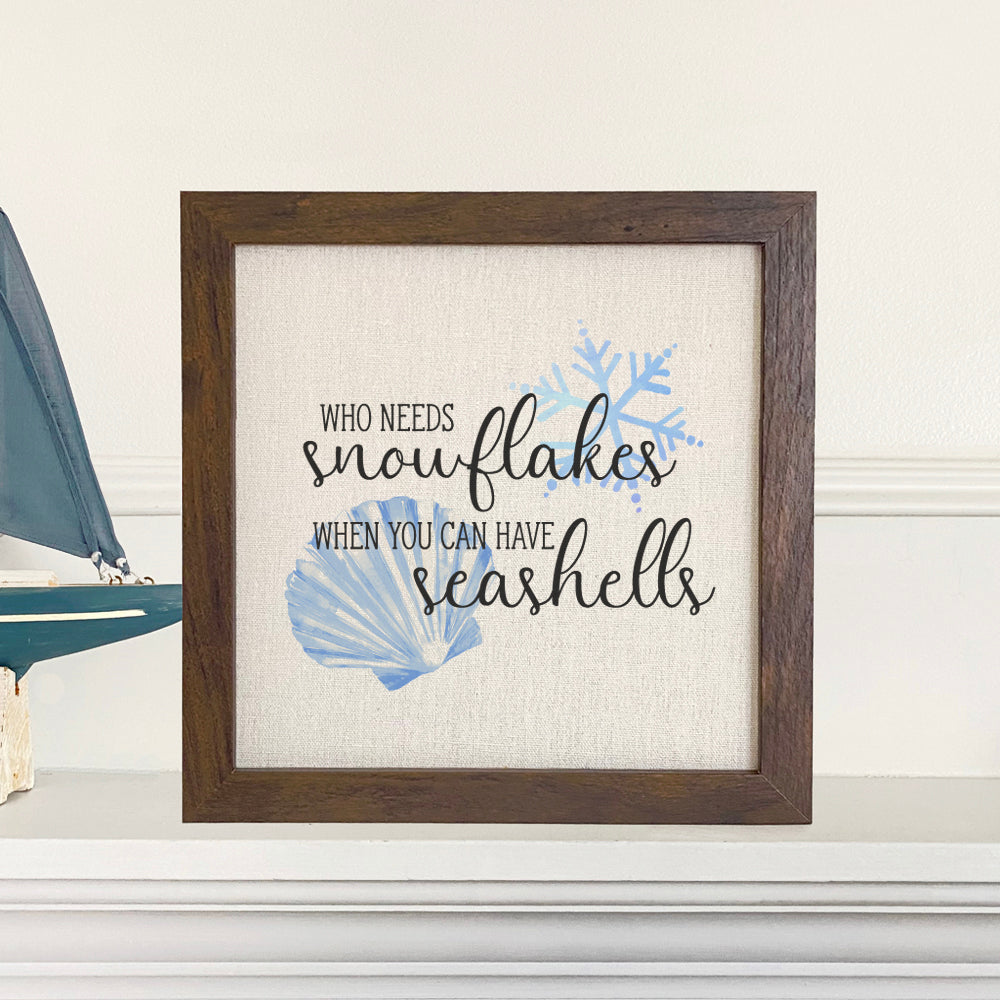 Snowflakes and Seashells Framed Sign with a wood frame and linen-look background, featuring intricate designs of snowflakes and seashells.