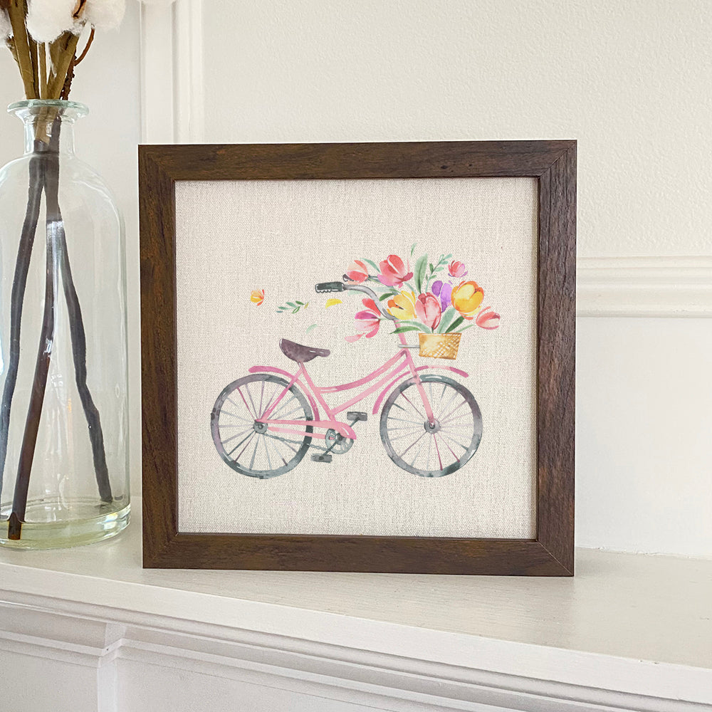 A beautifully framed sign featuring a floral bike design, set against a linen-look neutral background, perfect for home decor.