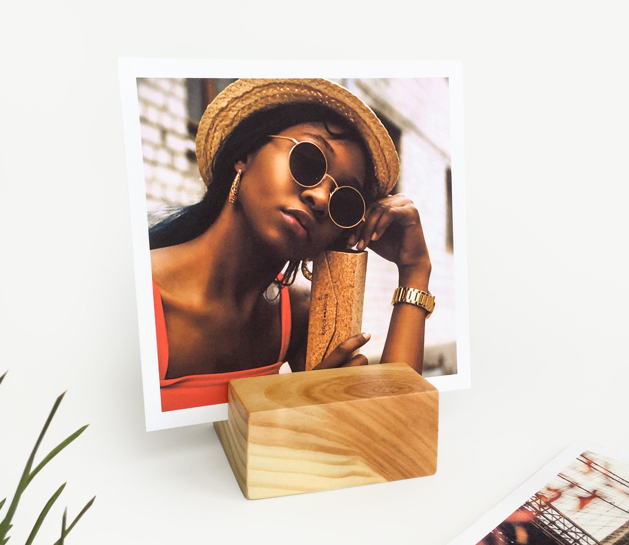 A handcrafted square wood card holder displaying various small art prints and photos, showcasing its eco-friendly design and natural finish.