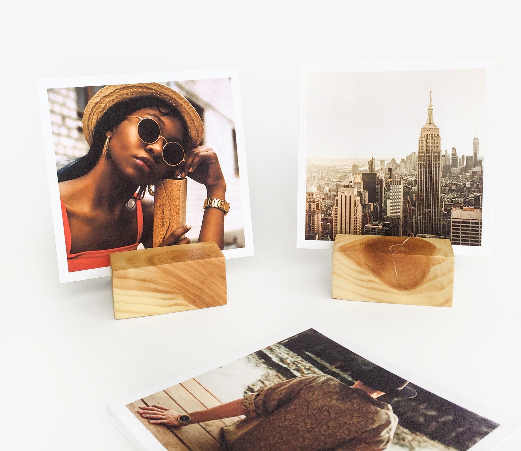 A handcrafted square wood card holder displaying various small art prints and photos, showcasing its eco-friendly design and natural finish.