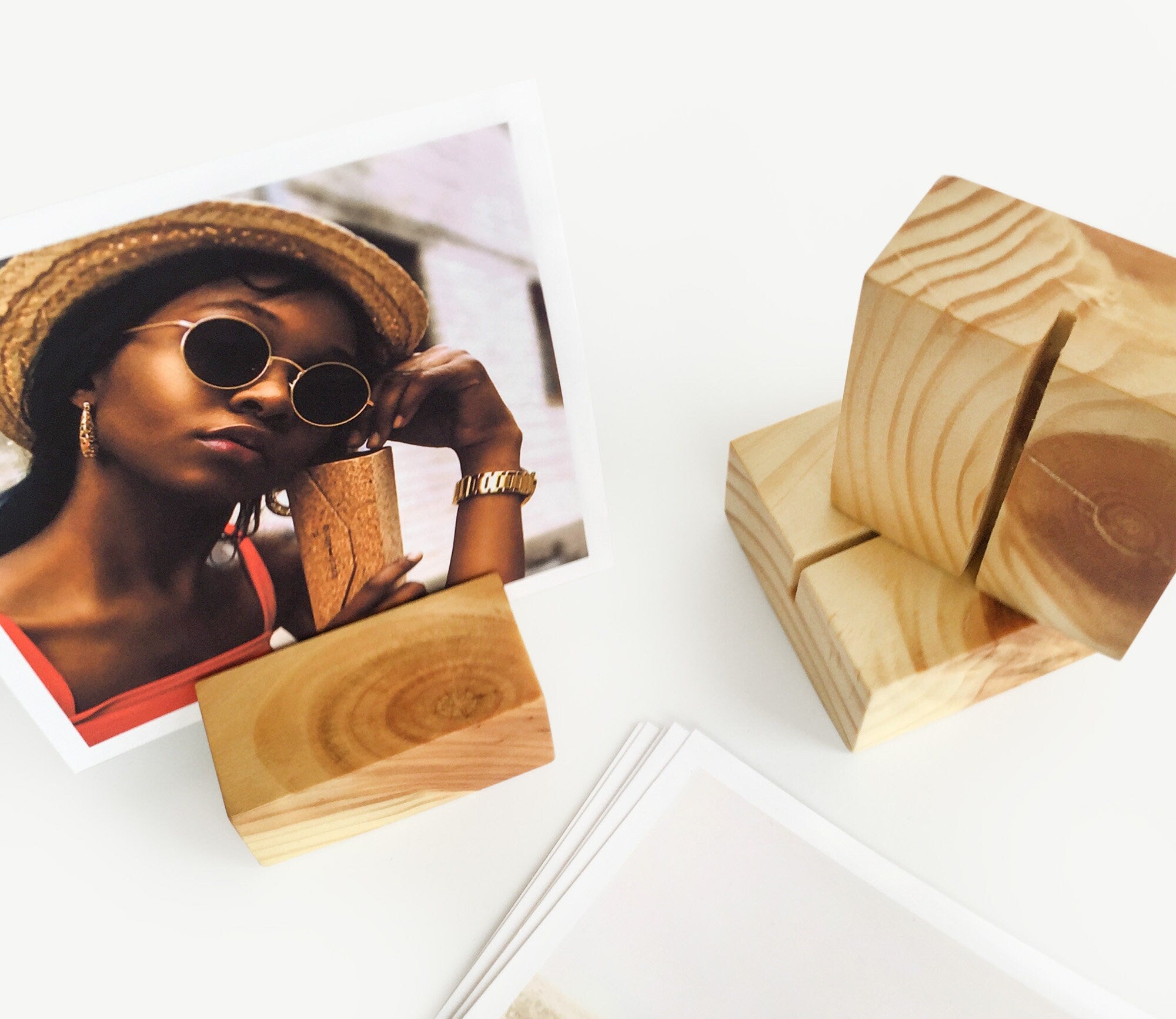 A handcrafted square wood card holder displaying various small art prints and photos, showcasing its eco-friendly design and natural finish.