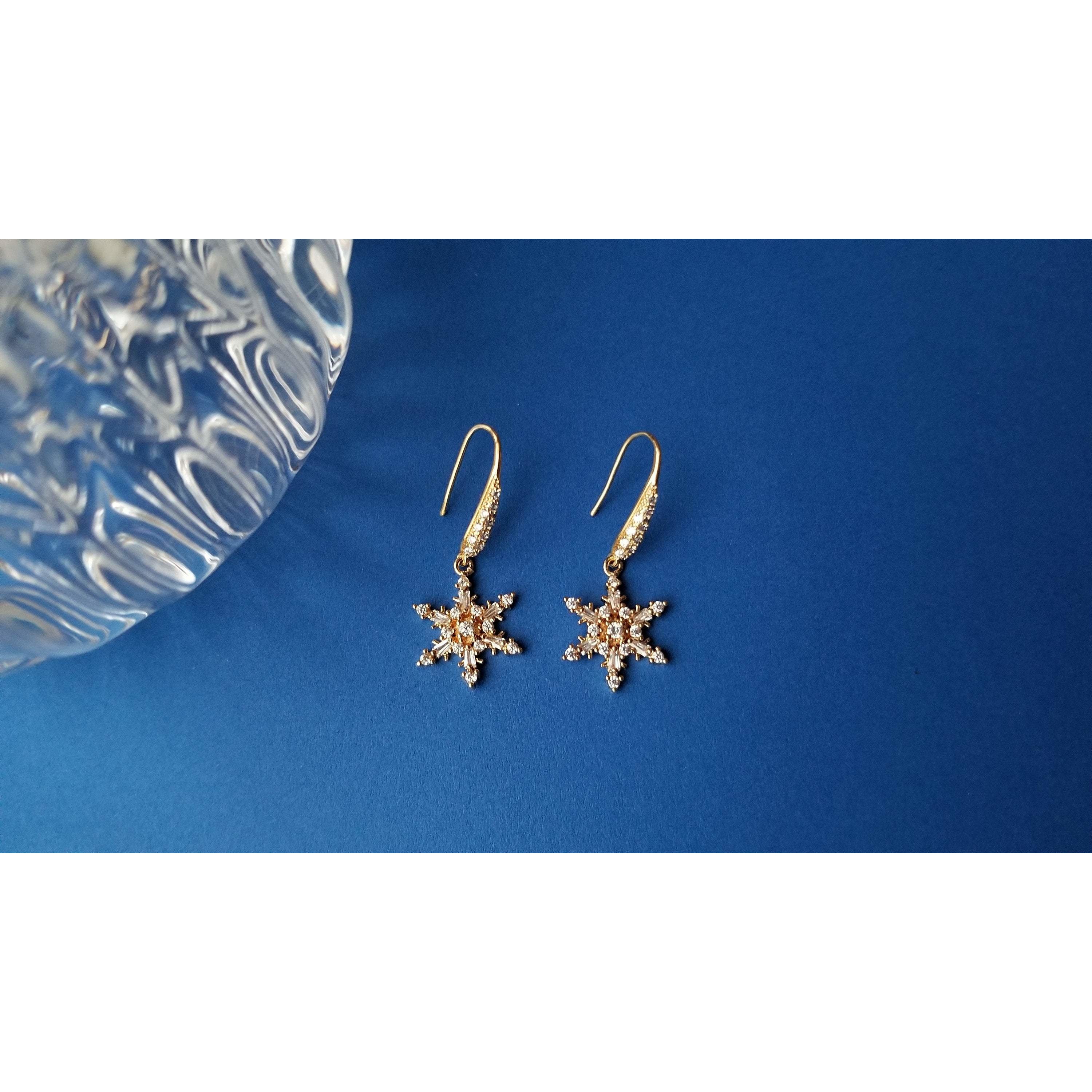 Elegant gold plated drop earrings featuring intricate snowflake design with sparkling cubic zirconia stones.