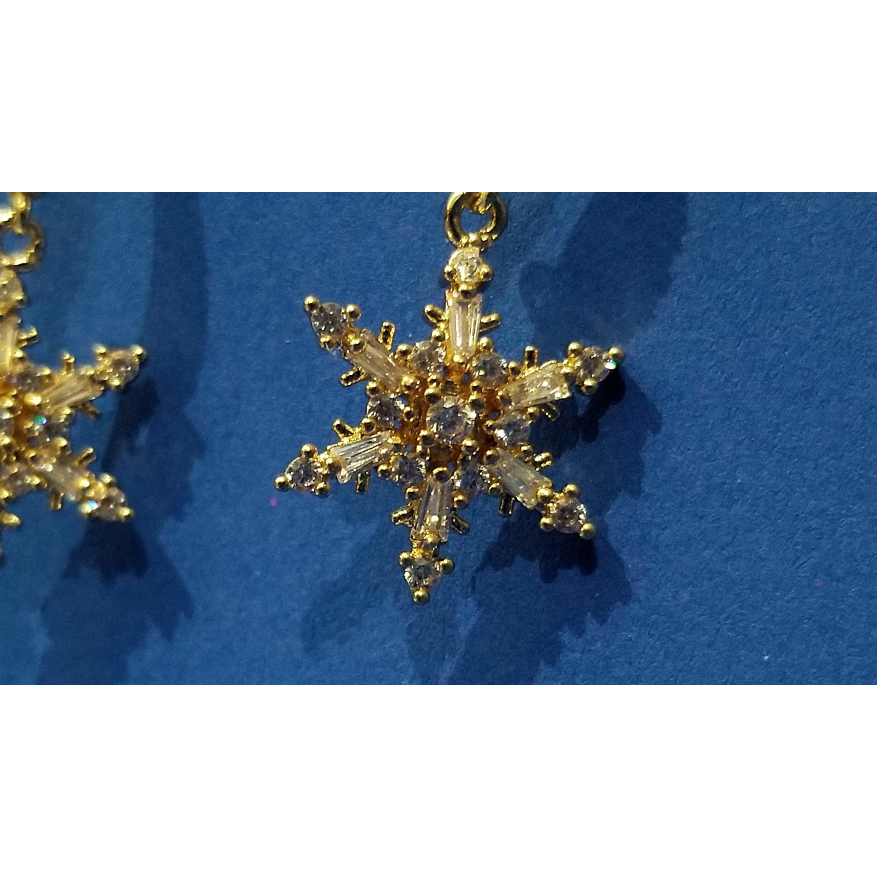 Elegant gold plated drop earrings featuring intricate snowflake design with sparkling cubic zirconia stones.