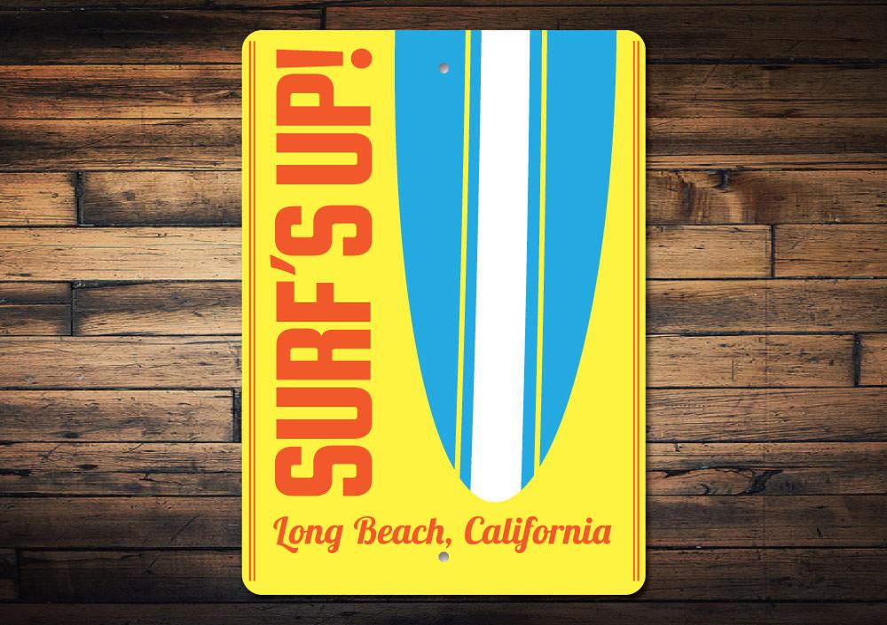 A decorative Surf's Up sign made of aluminum, featuring vibrant colors and beach-themed design, perfect for coastal decor.