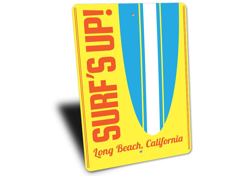 A decorative Surf's Up sign made of aluminum, featuring vibrant colors and beach-themed design, perfect for coastal decor.