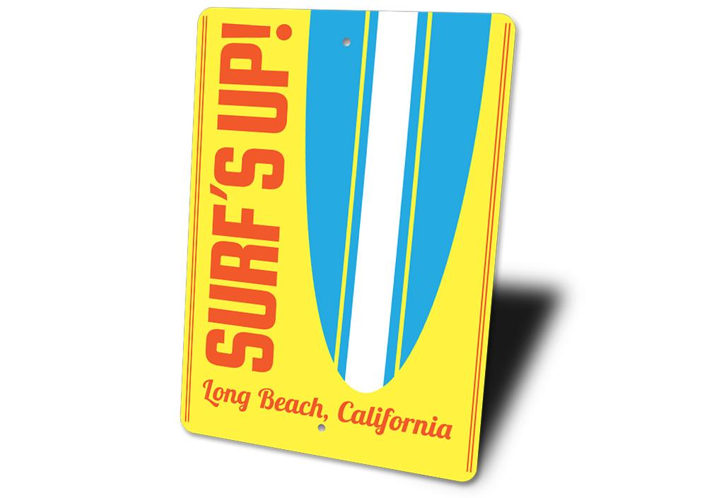 A decorative Surf's Up sign made of aluminum, featuring vibrant colors and beach-themed design, perfect for coastal decor.