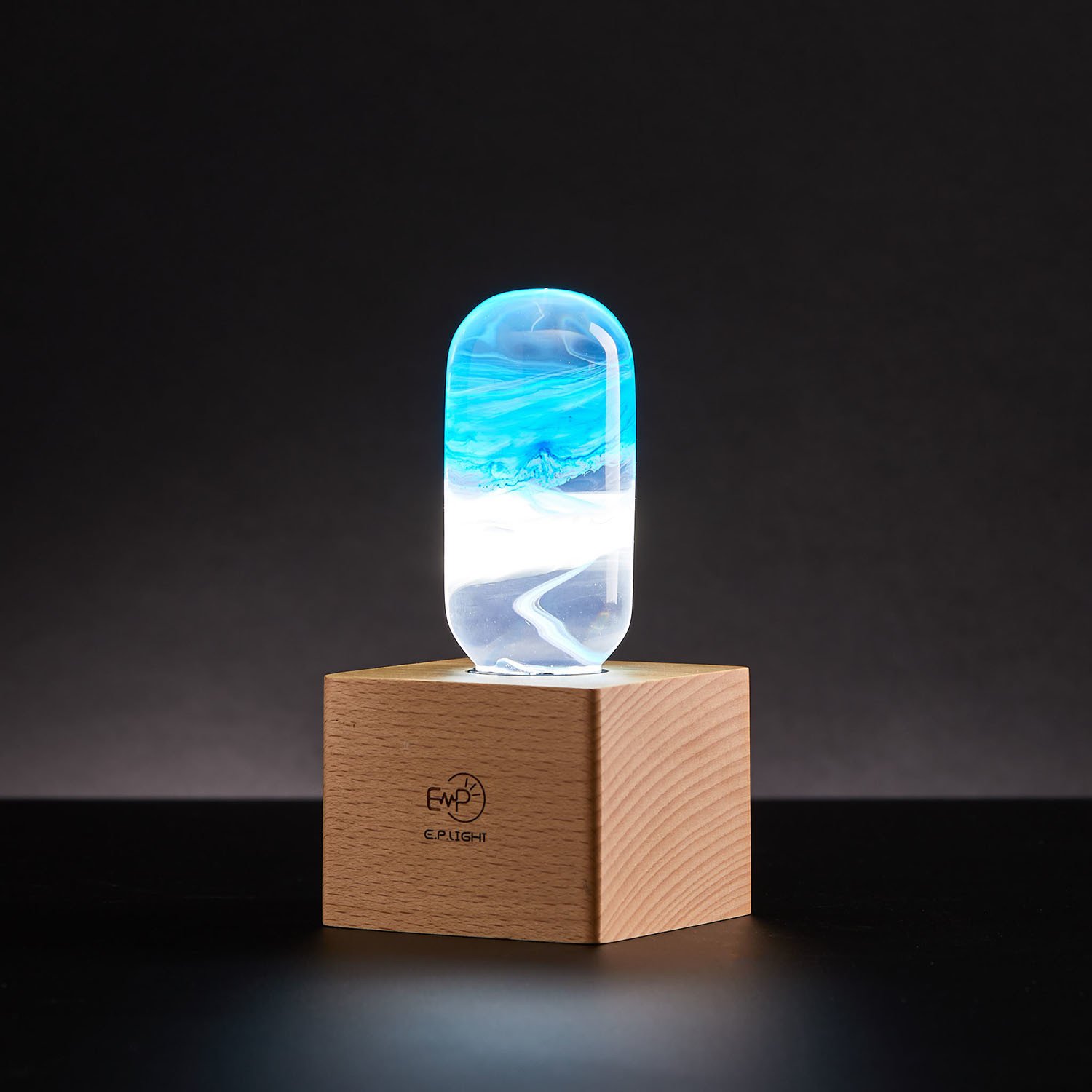 A stylish blue table lamp made from eco-friendly resin and beech wood, featuring an LED bulb and a modern design.